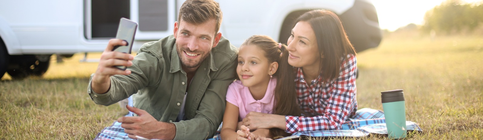 a family of three taking a selfie outdoors.