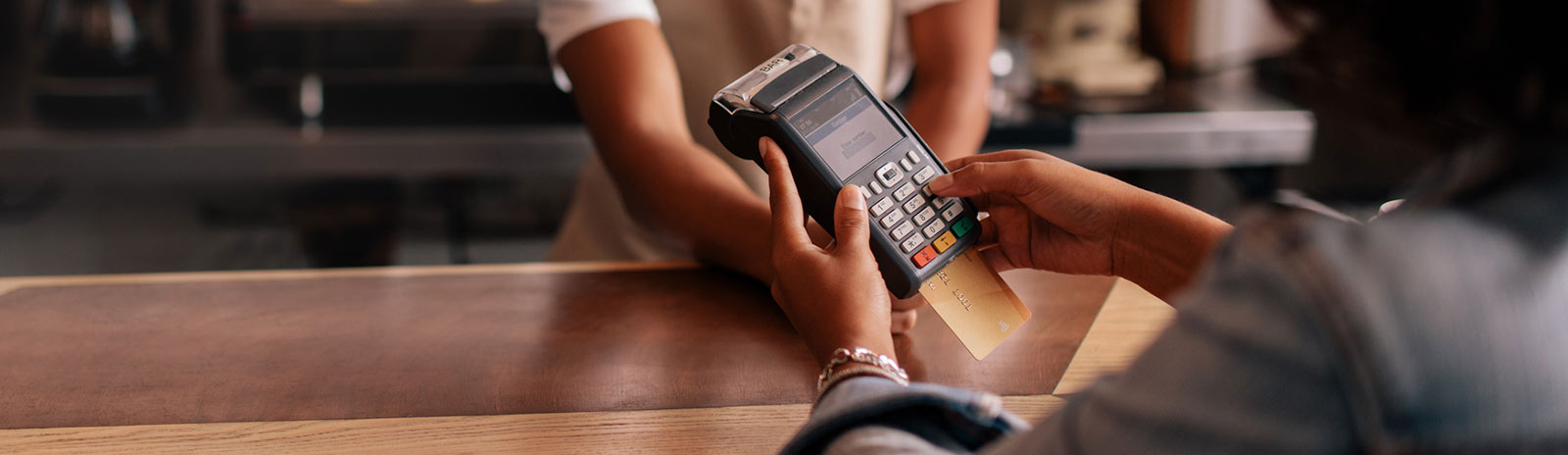 Woman using card reader to pay at cafe.